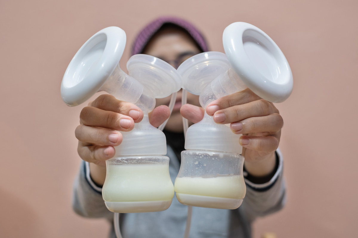 woman holding two breast pumps filled with human donor milk